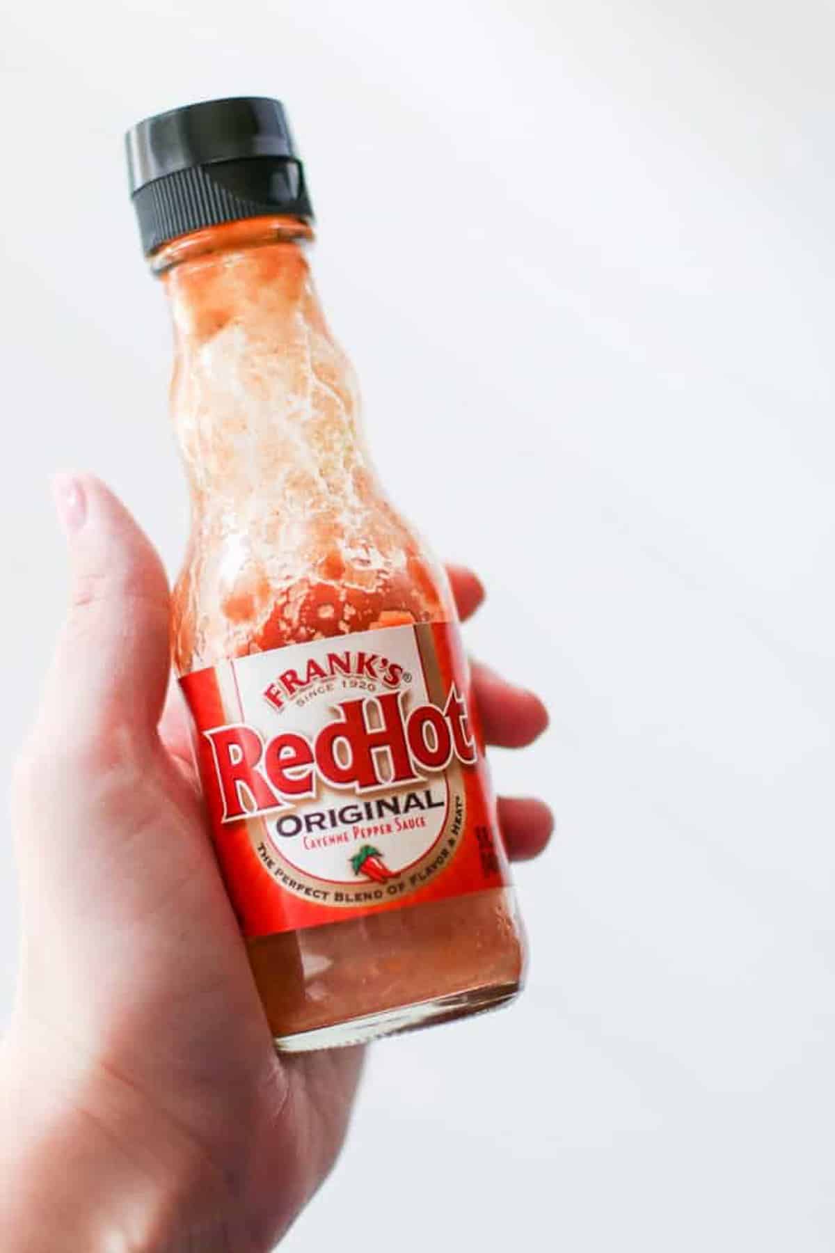 A hand holding a Franks Hot sauce bottle. 