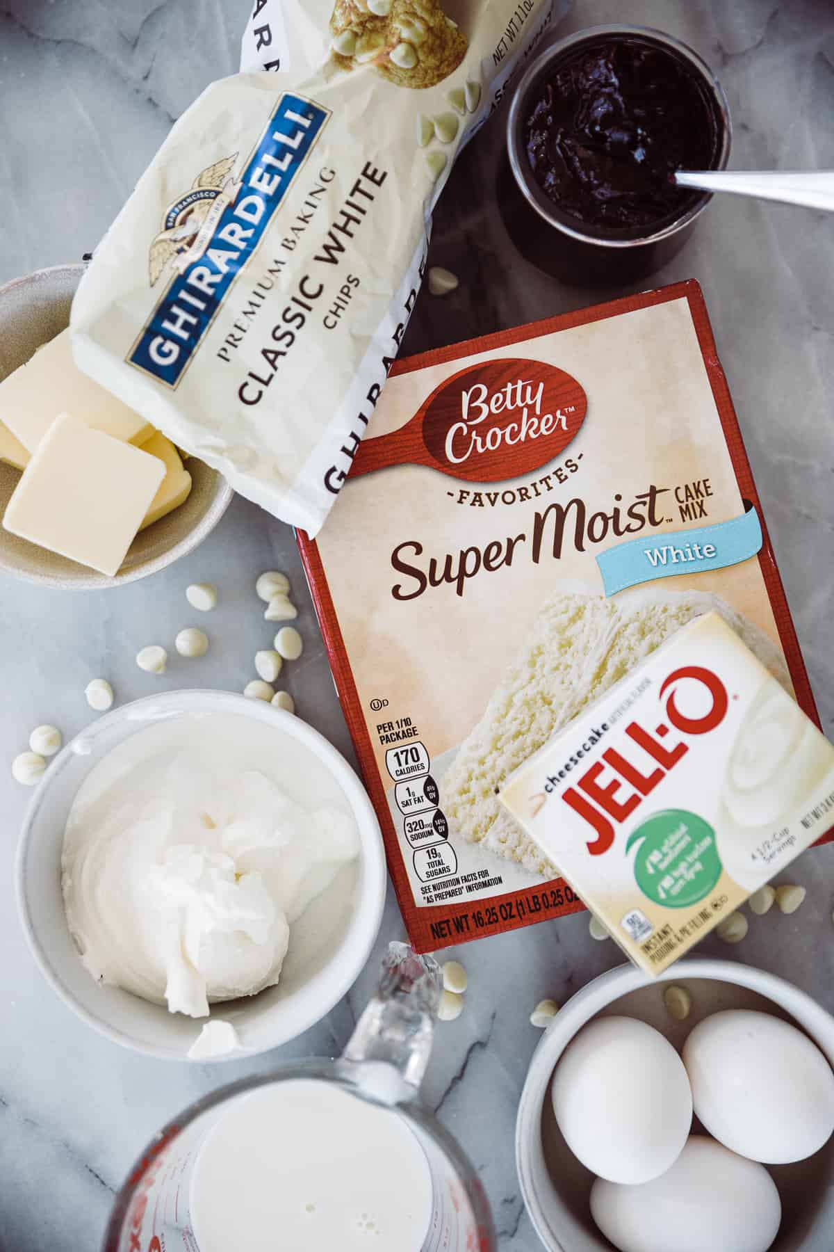 Ingredients for white chocolate raspberry cake with preserves, cake mix and other items. 
