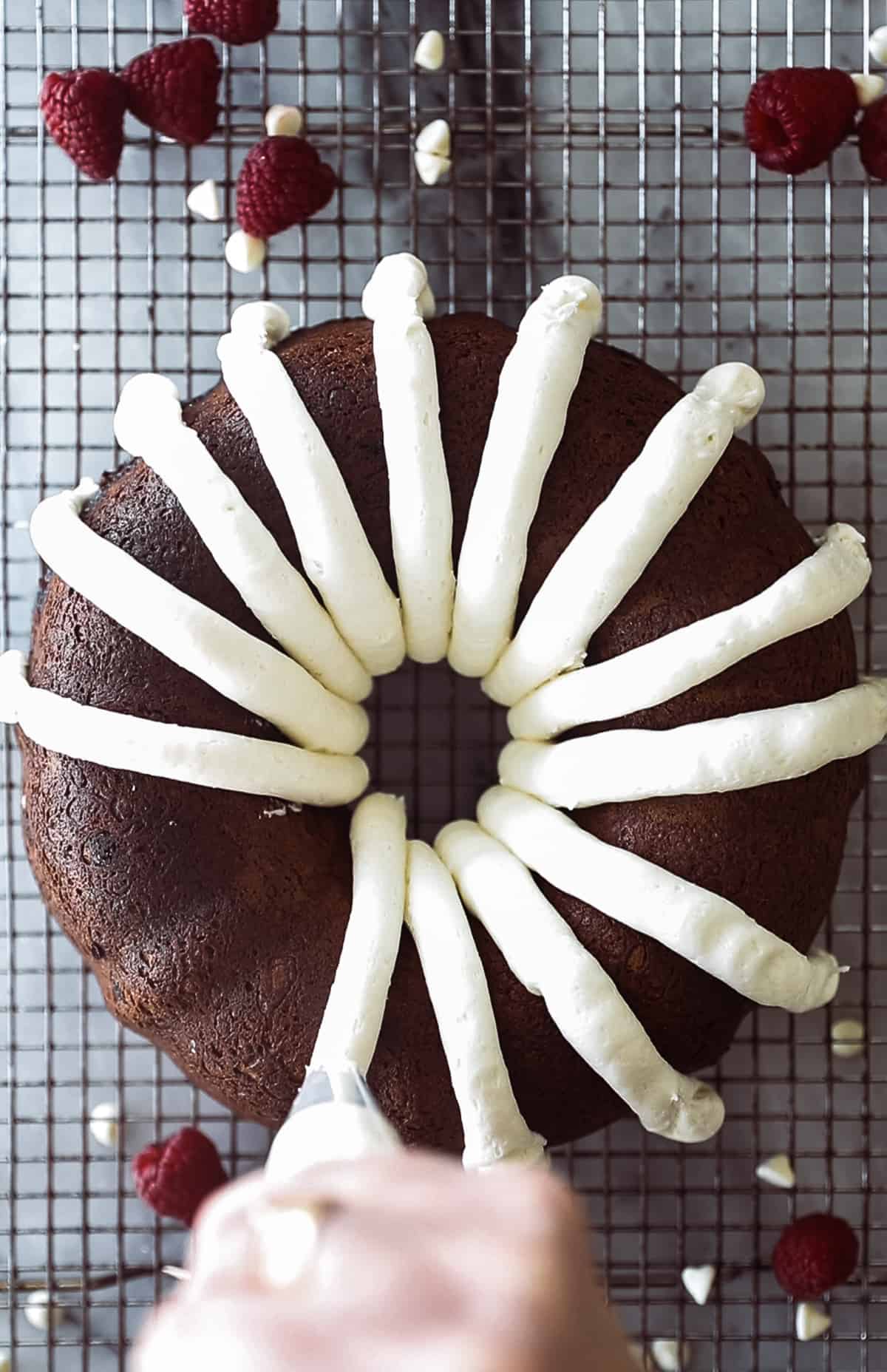 Bake bundt pan with cream cheese frosting being pipped on top. 