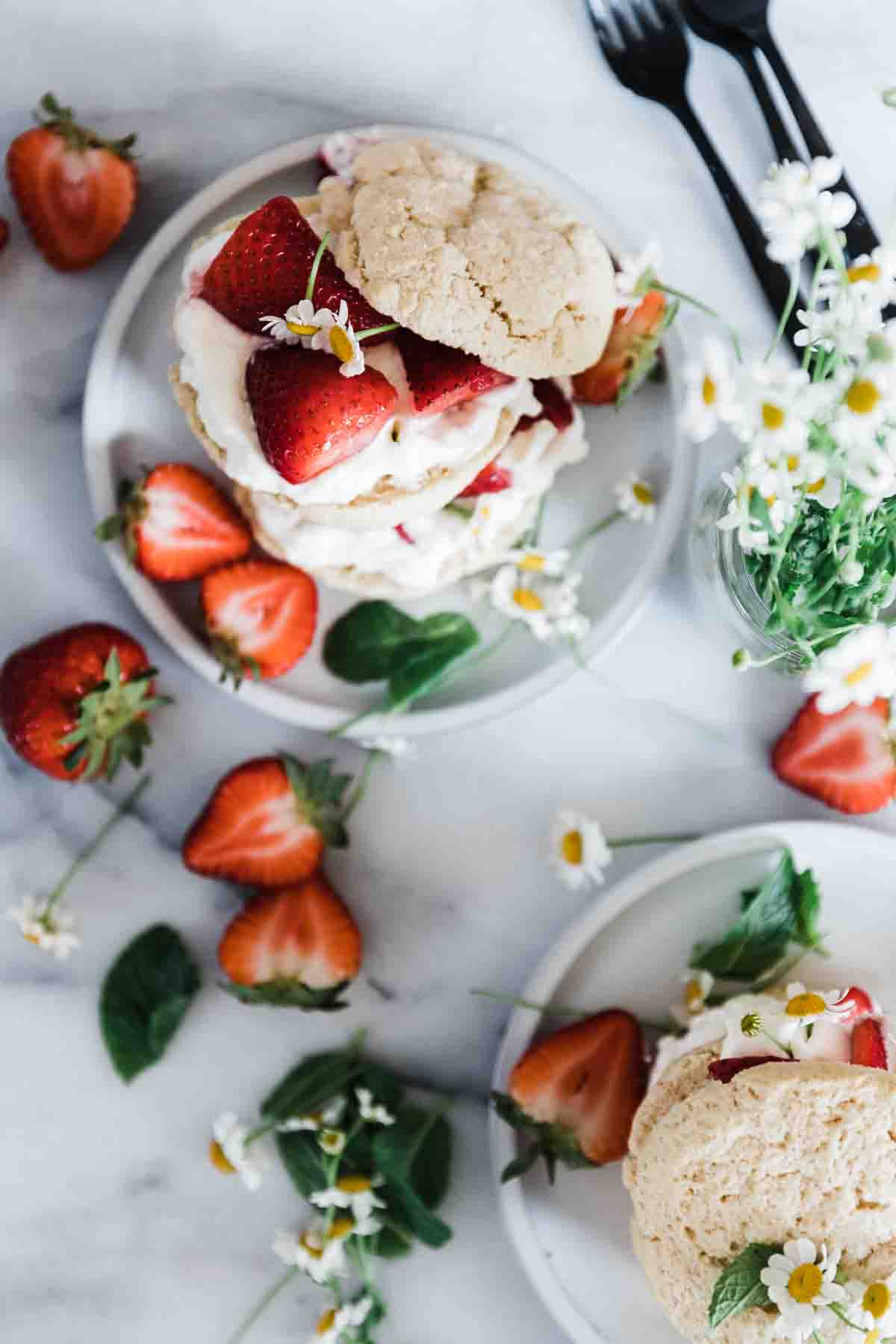 Easy strawberry shortcake on grey plates with sliced strawberries scattered around.