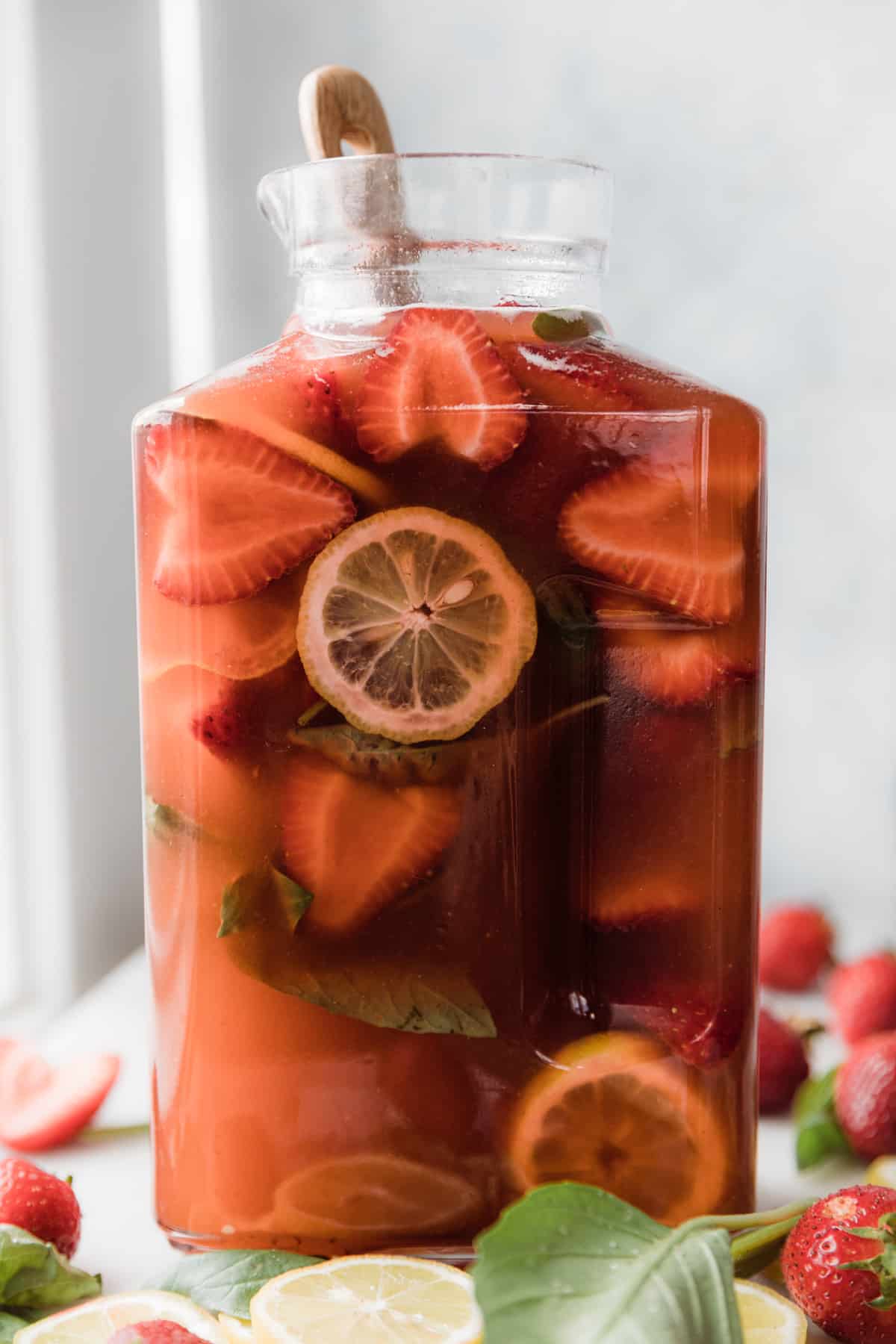 Strawberries, lemons and basil in a pitcher of strawberry lemonade. 