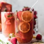 Large Glass of strawberry basil lemonade with glass straw.