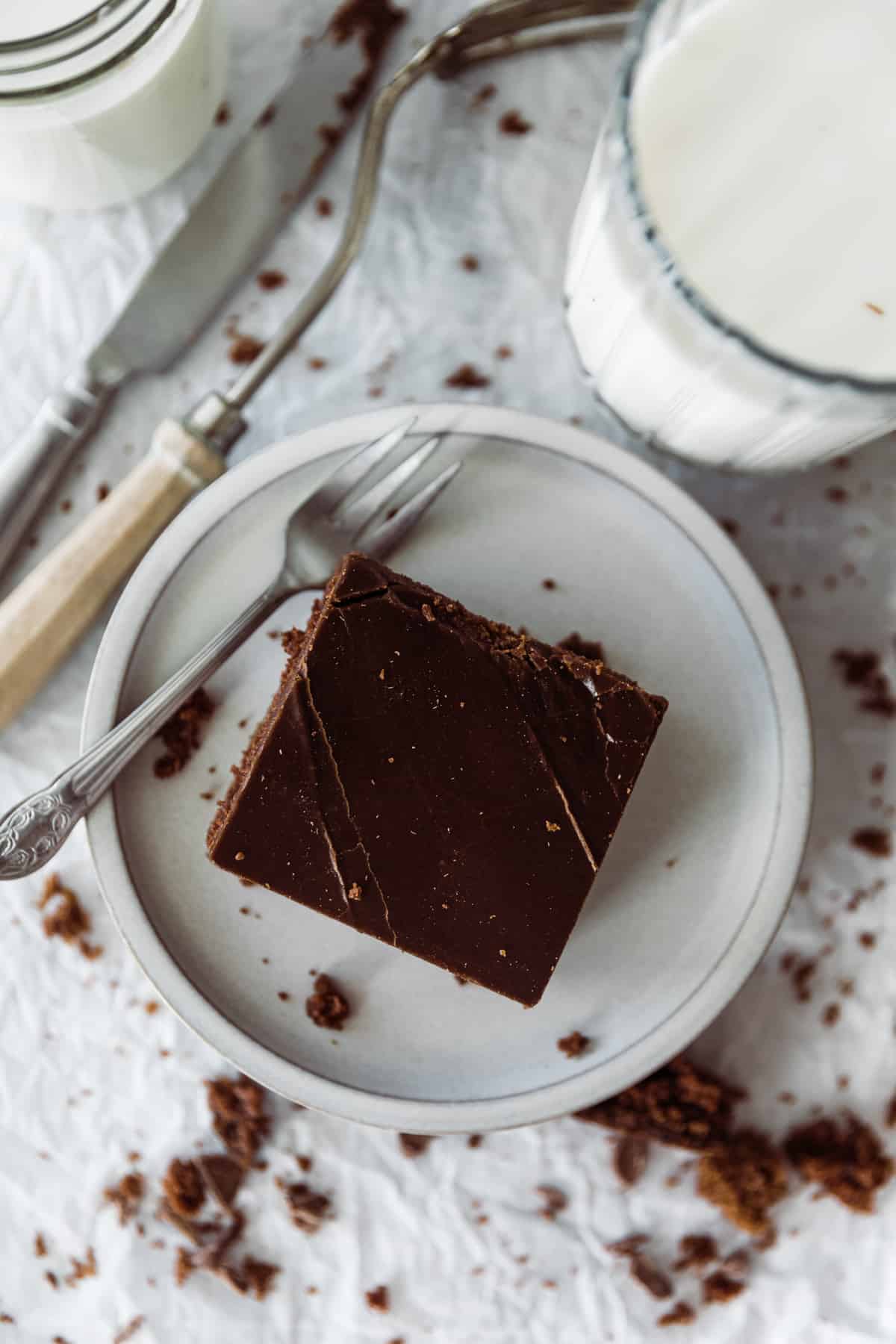 One slice of chocolate sheet cake on a dessert plate with a cup of milk. 