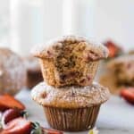 Two muffins stacked on top of each other. There is a bite taken out of the top muffin.