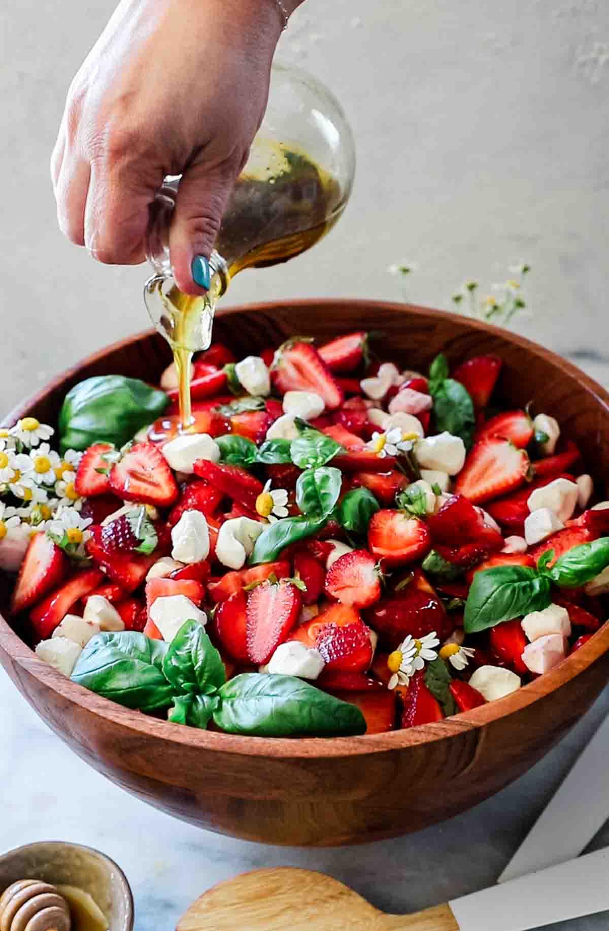 Dressing being poured onto strawberry caprese salad.