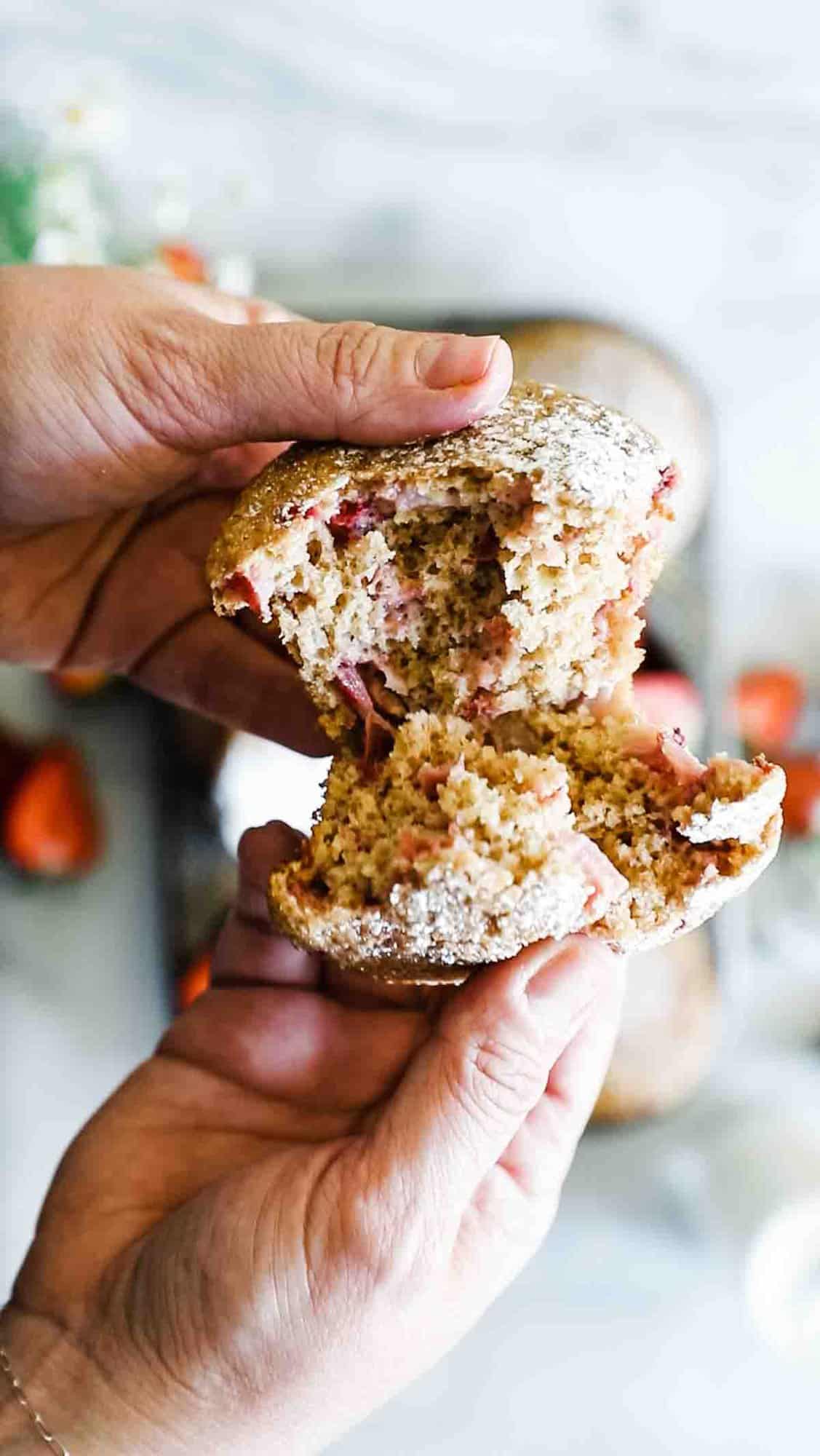 A healthy strawberry muffin being pulled apart.