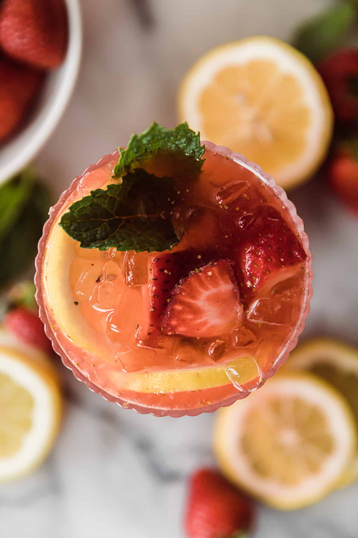 Flat lay of strawberry lemonade with strawberries, lemons and a mint leaf. 