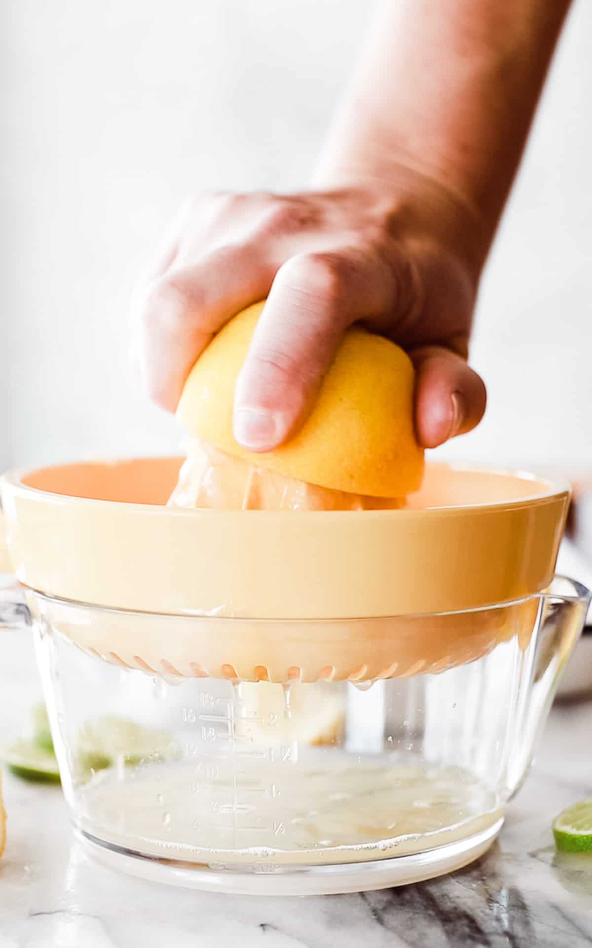 A hand juicing a lemon with a hand juicer. 