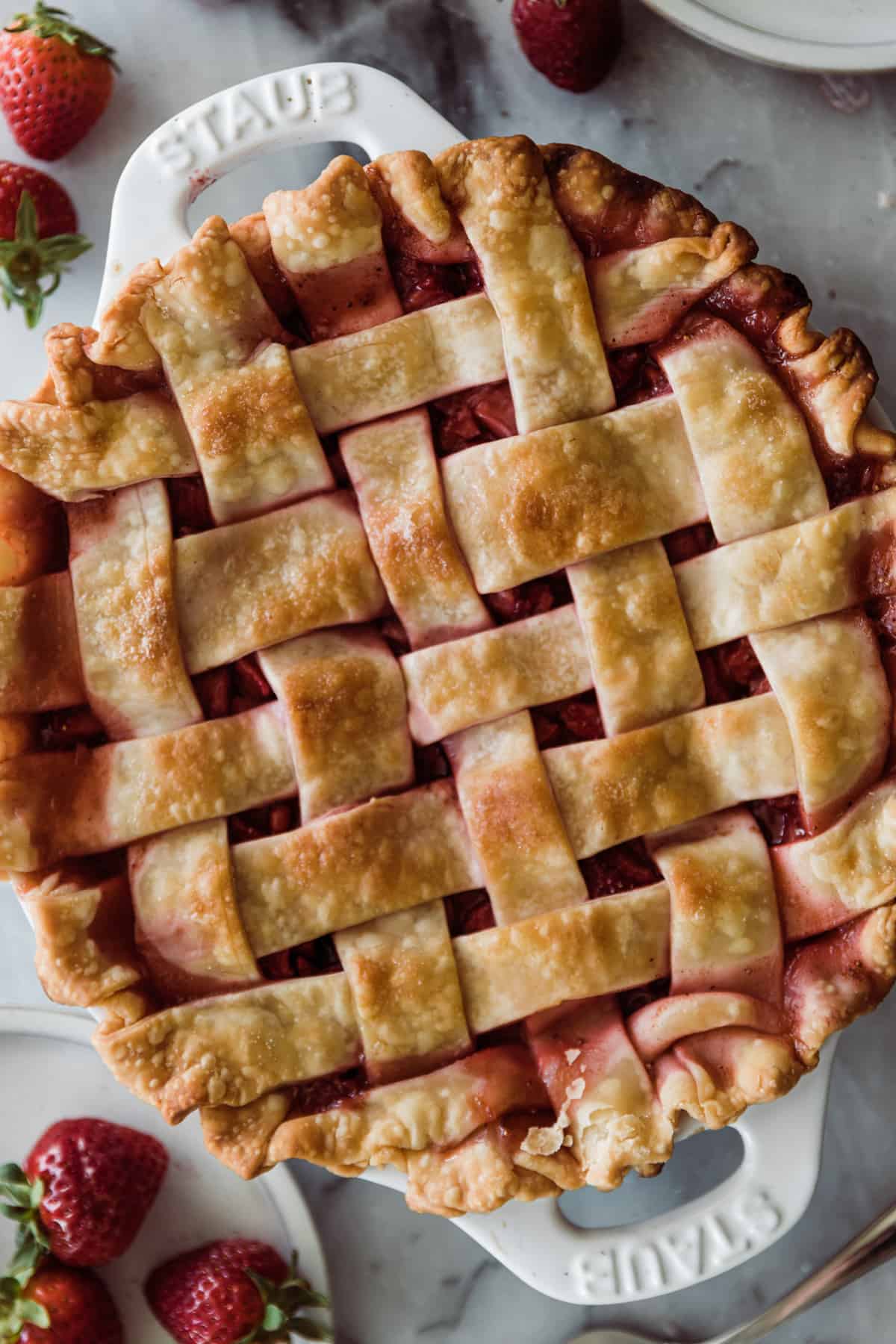 Golden brown baked strawberry pie with red juices. 