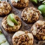 Apple muffins in a muffin tin surrounded by Granny Smith apples.