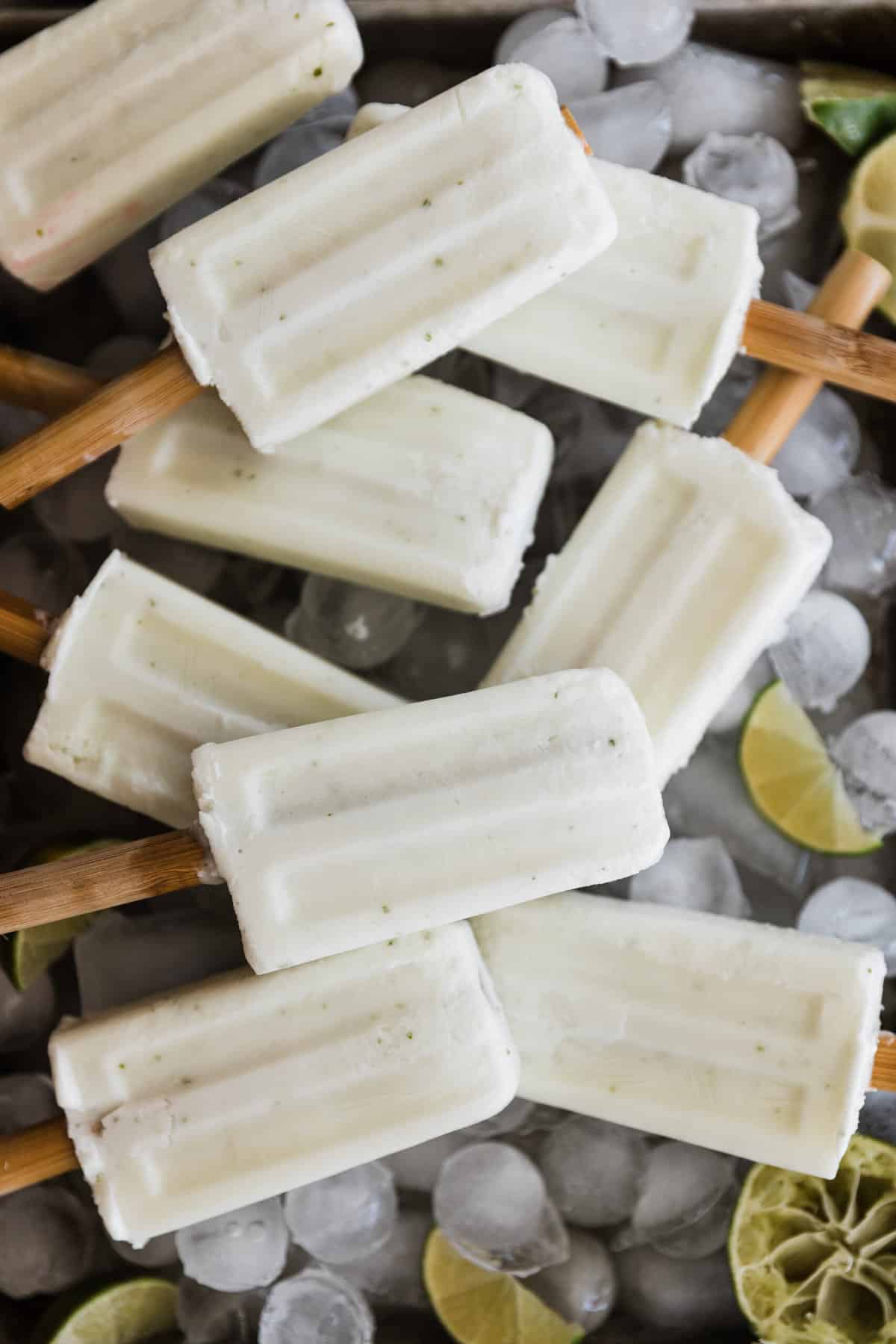 Creamy coconut lime popsicles on a tray of ice cubes. 