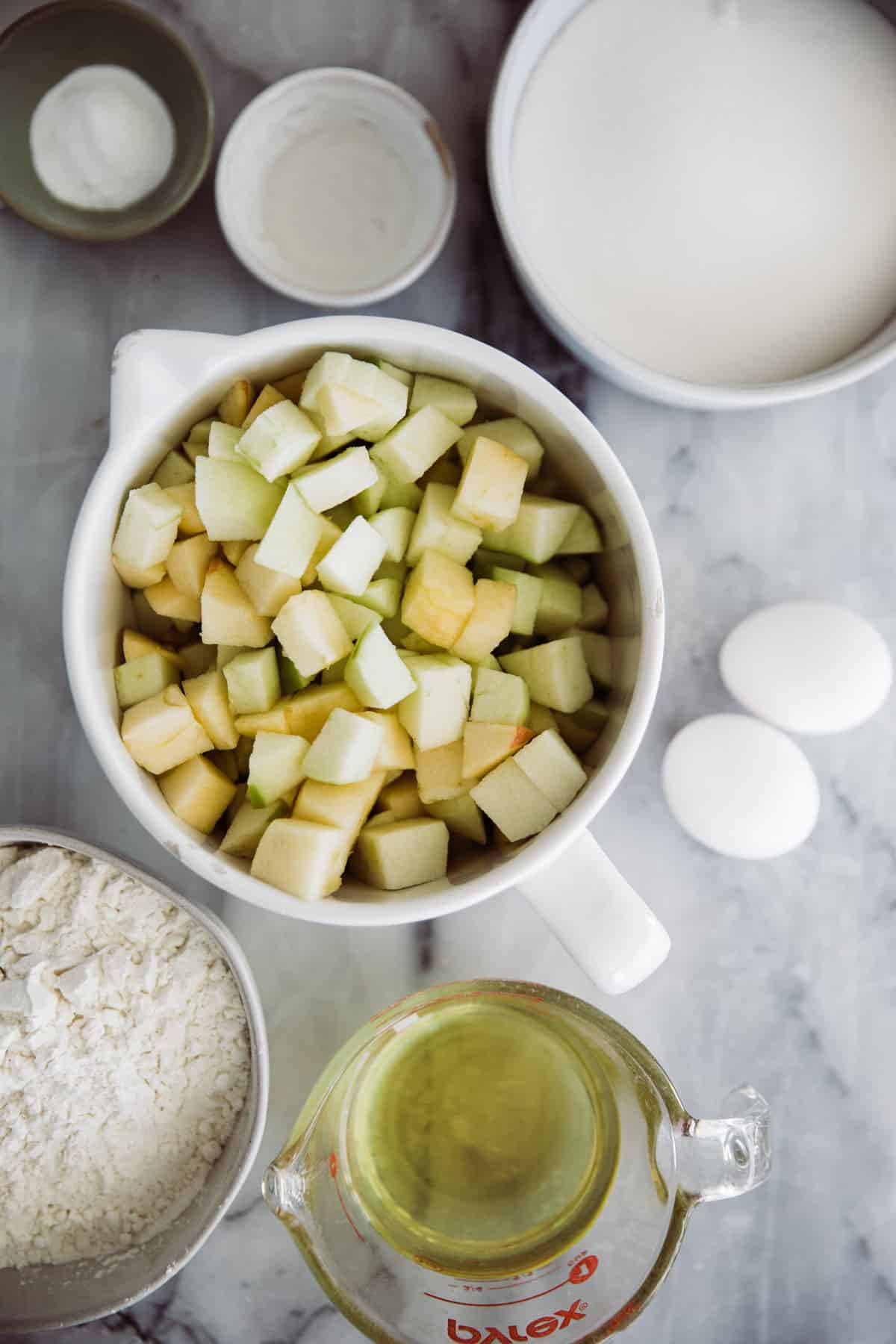 Apple Cake ingredients in separated into bowls on a marble platter. 
