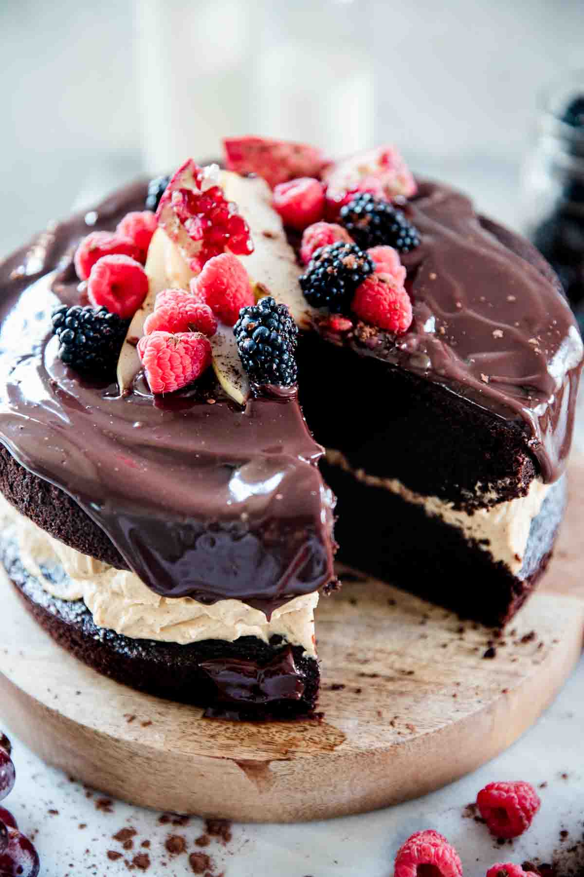 A close up of chocolate pumpkin cake. It has a pumpkin filling and is garnished with berries.