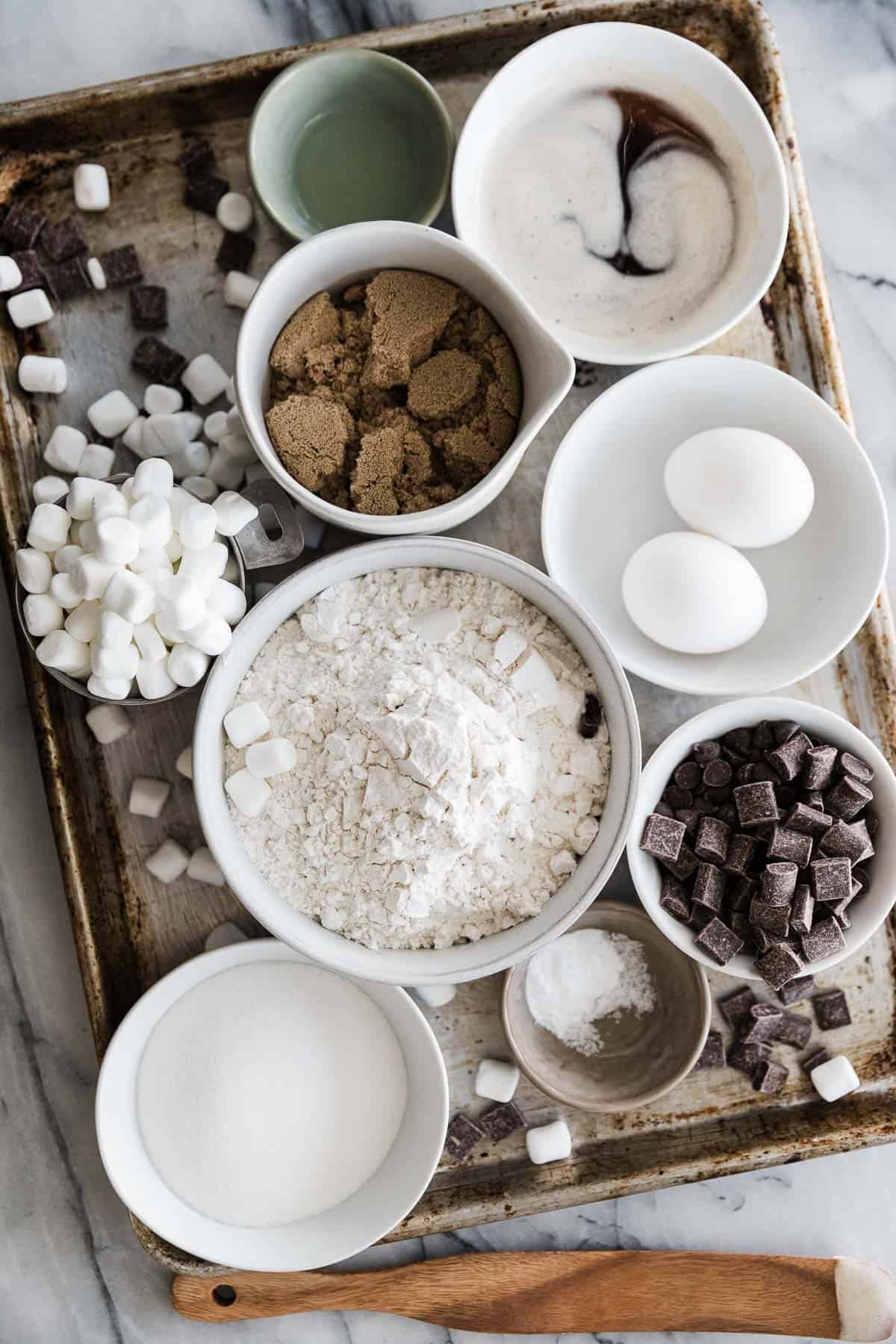 Bowls of smores cookie ingredients on a baking tray. 