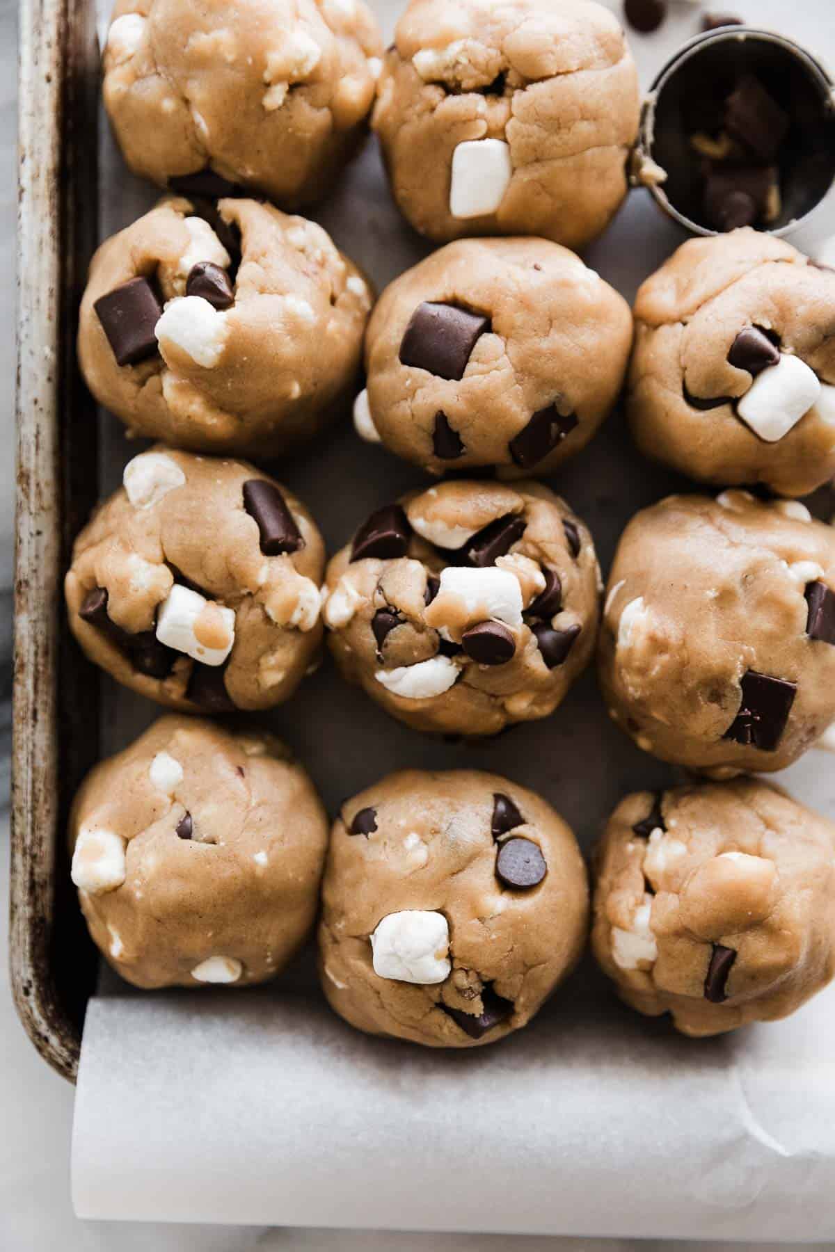 Several cookie dough balls on a baking sheet. 
