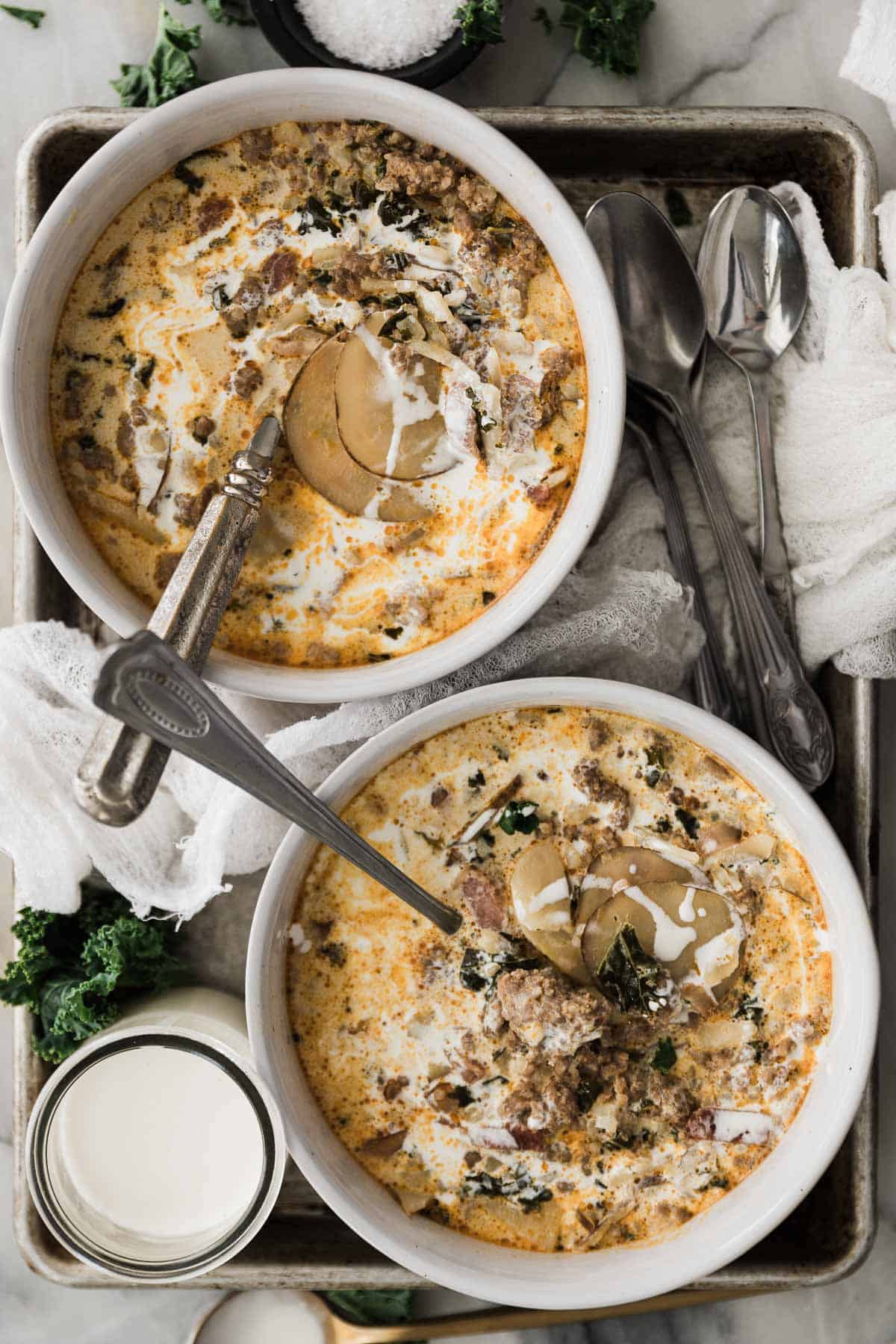 Two bowls of Olive Garden copycat recipe zuppa Toscana on a tray with spoons. 
