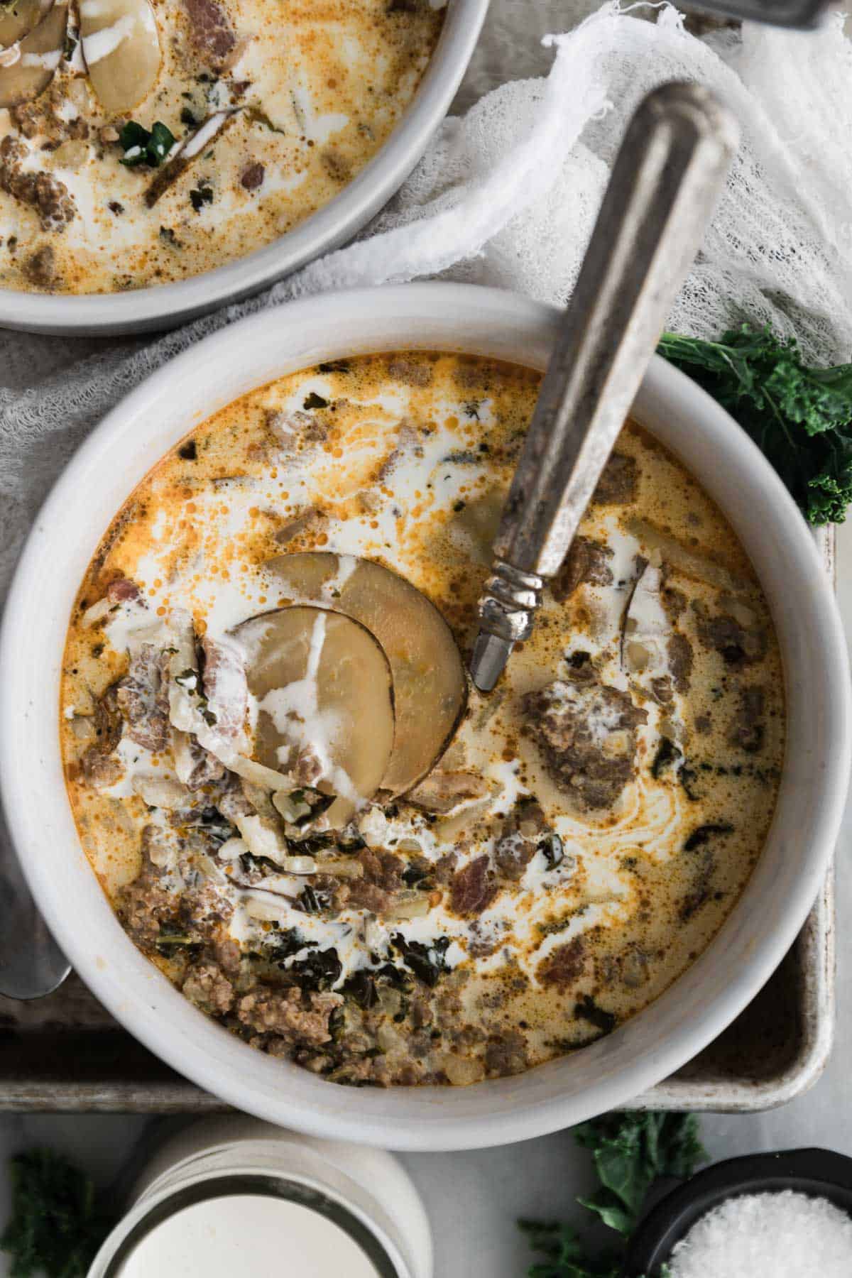 Creamy Zuppa Toscana soup recipe in a bowl on a tray with a spoon. 