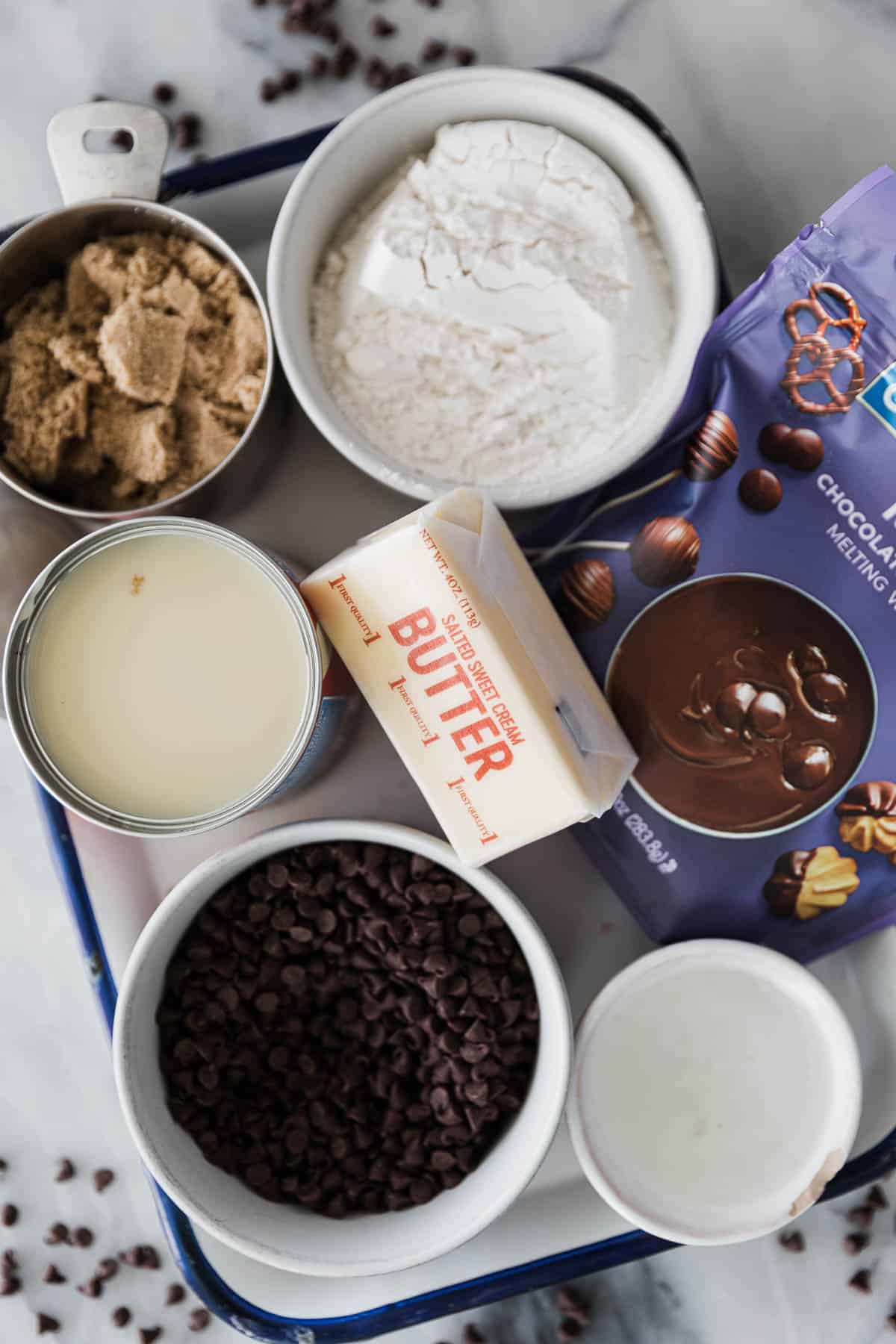 Ingredients for chocolate chip cookie dough bites in bowls on a tray. 
