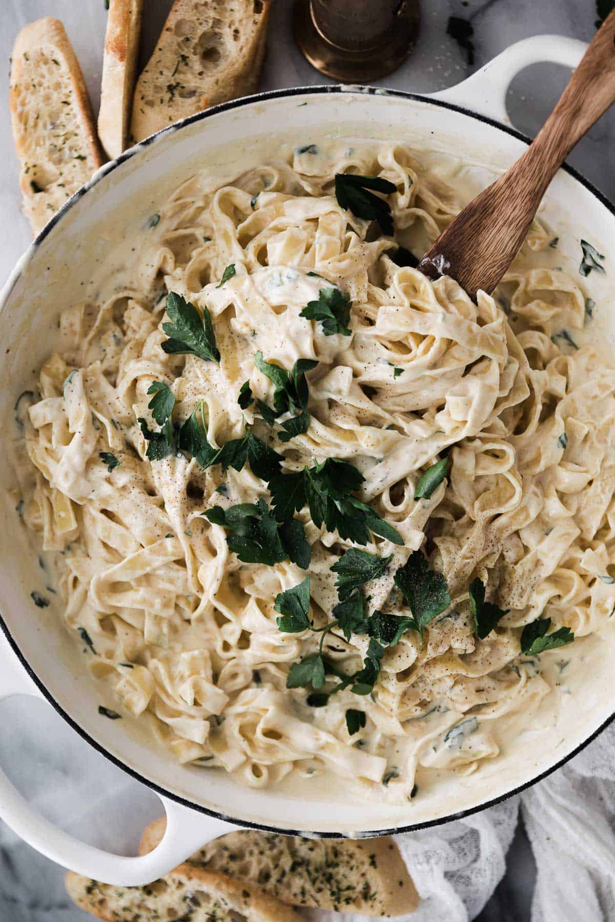 Fettuccine Alfredo in a large pot topped with parsley. 