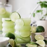 One cup with a straw and lime garnish filled to the top with a frozen mojito mocktail.