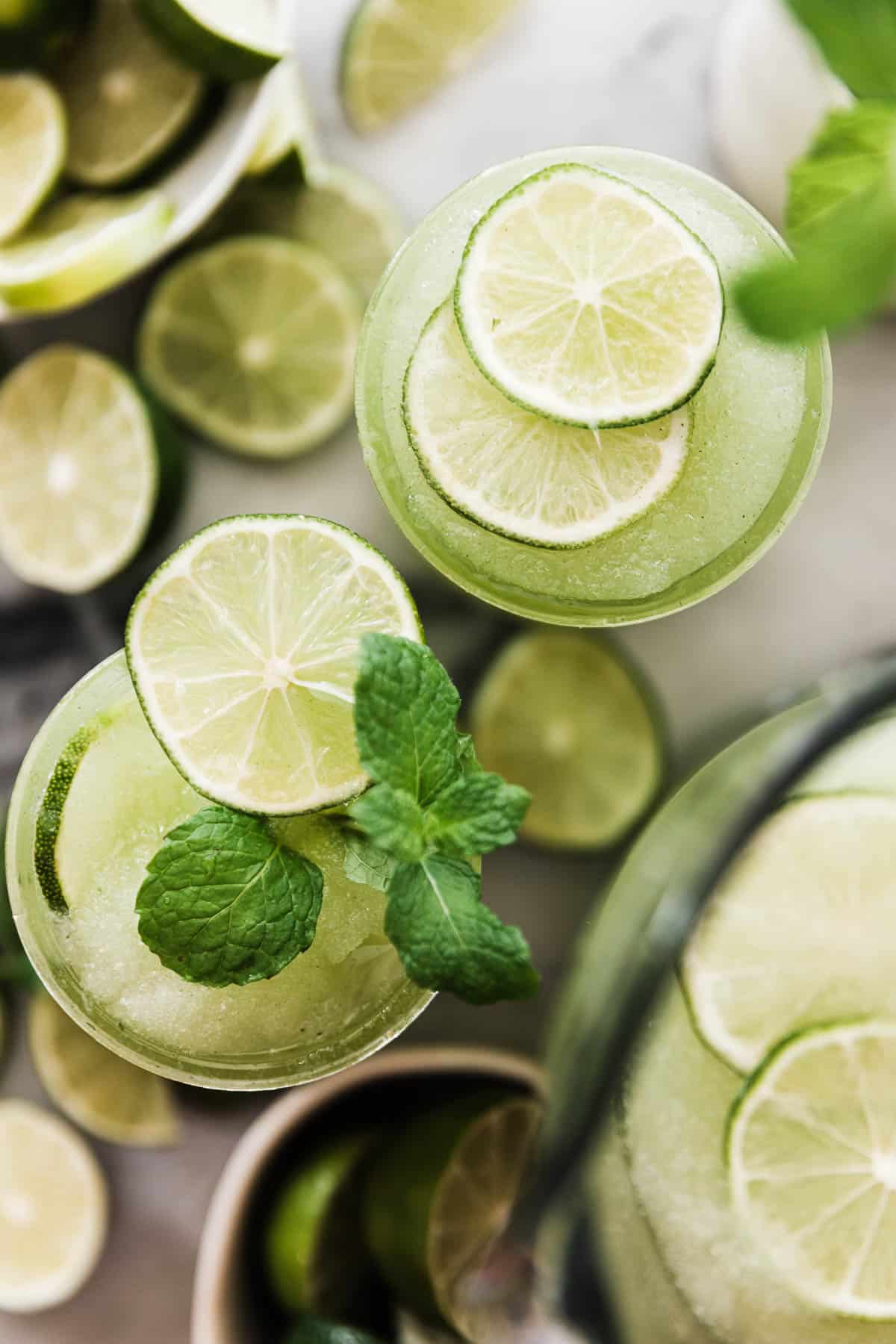 Birds Eye view of two cups filled with mojito mocktail with limes and mint as garnishes.