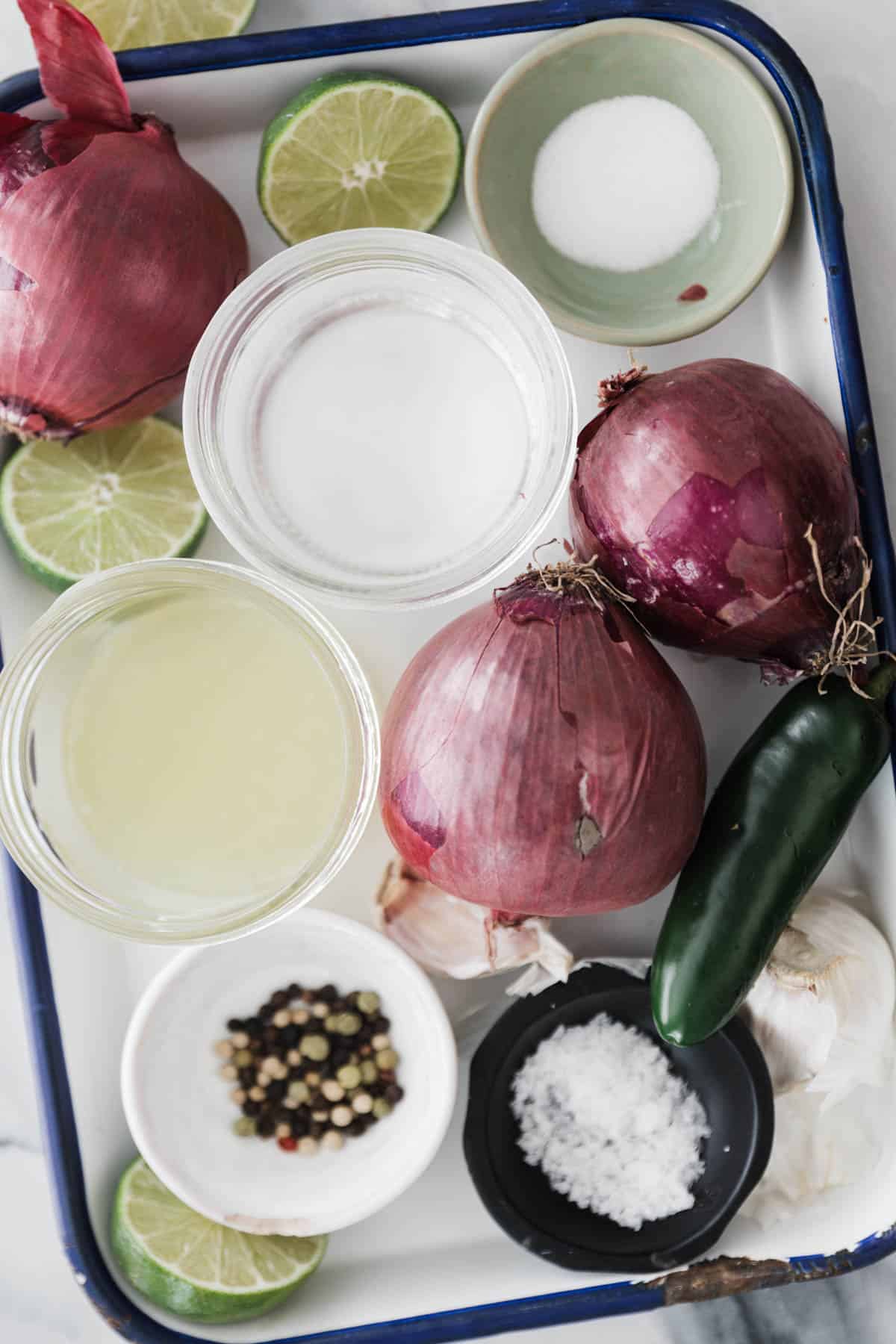 Tray of onions, salt, jalapeño, limes and other spices for making pickled red onions.