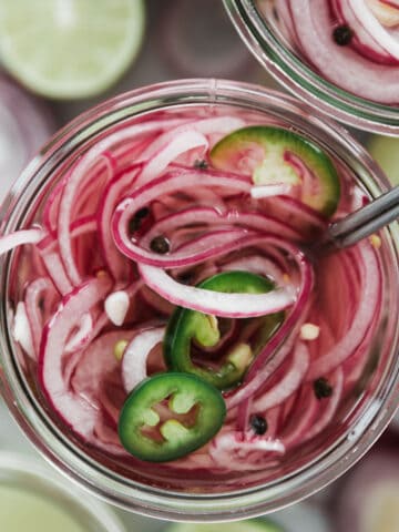 Top down photo of a jar filled with sliced red onions vinegar, spices and sliced jalapeños.