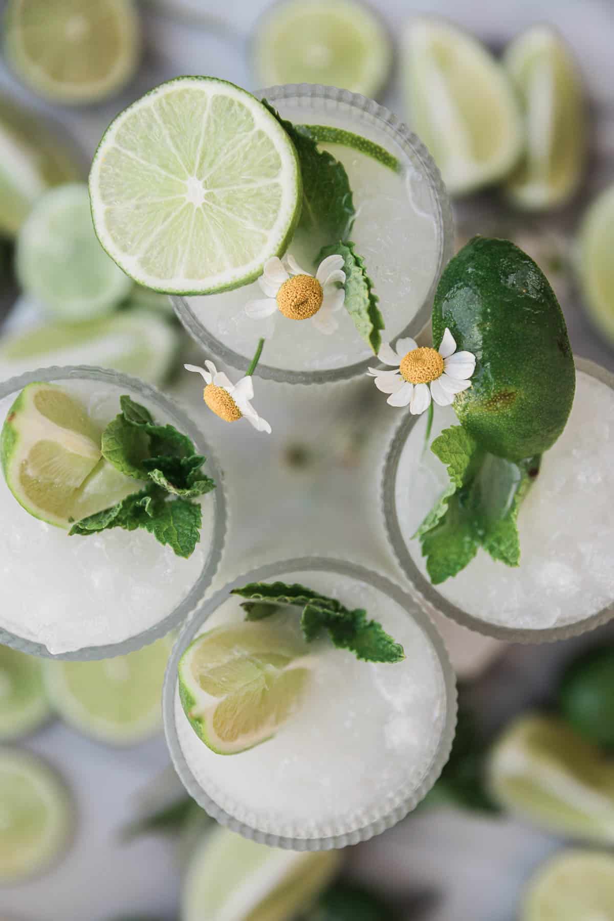 An overhead shot of Brazilian limeade, The glasses are garnished with mint and limes.