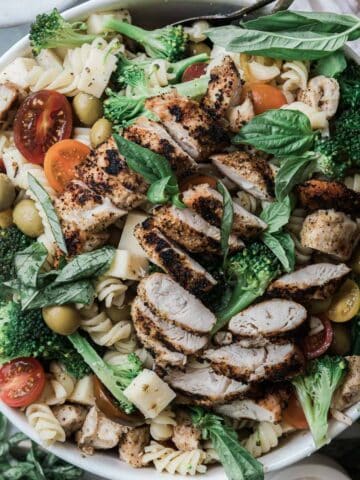 A bowl of chicken pasta salad with grilled chicken on top.