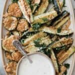 Air fryer zucchini on a platter with a bowl of ranch.