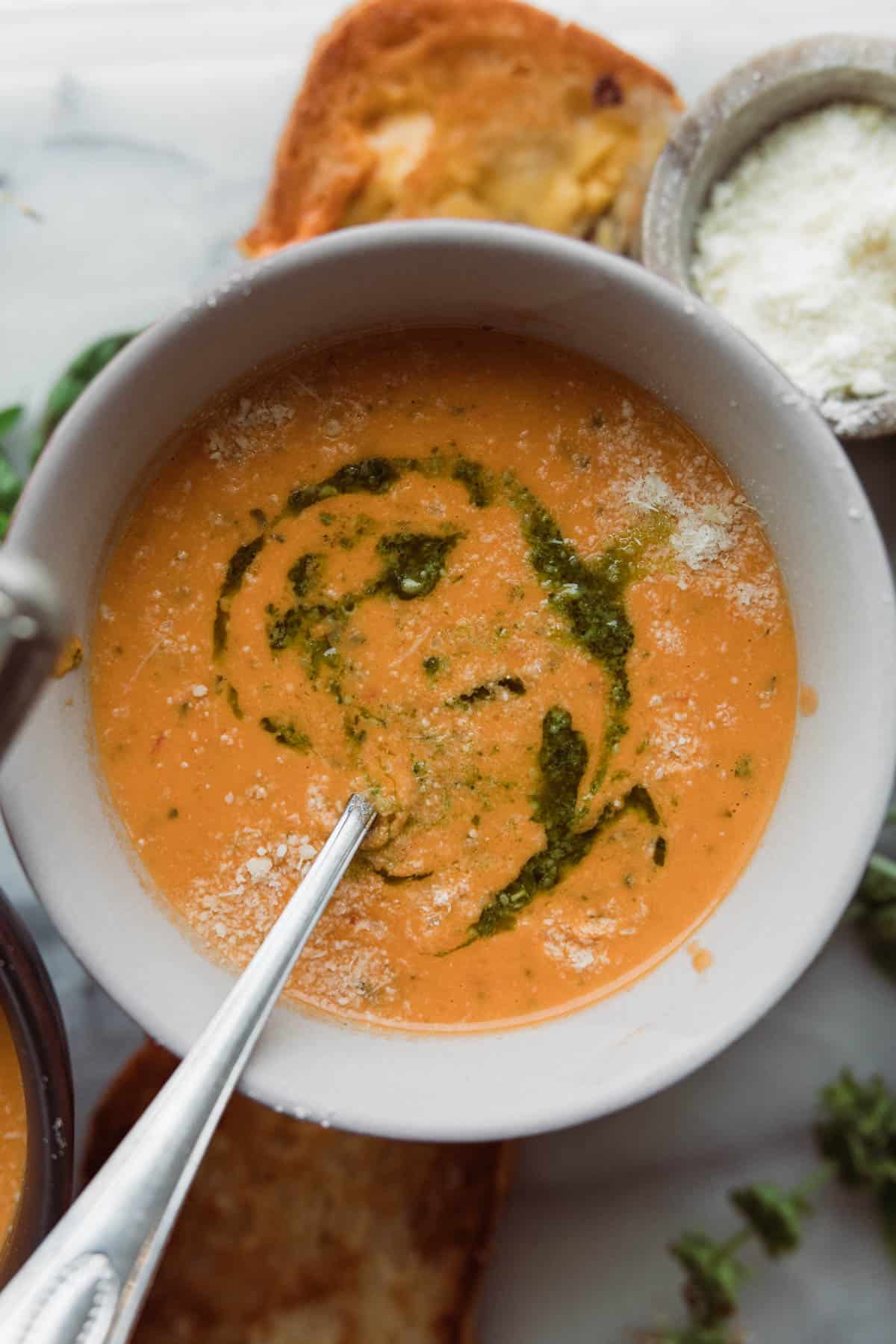 Bowl of creamy tomato basil soup with a drizzle of basil.
