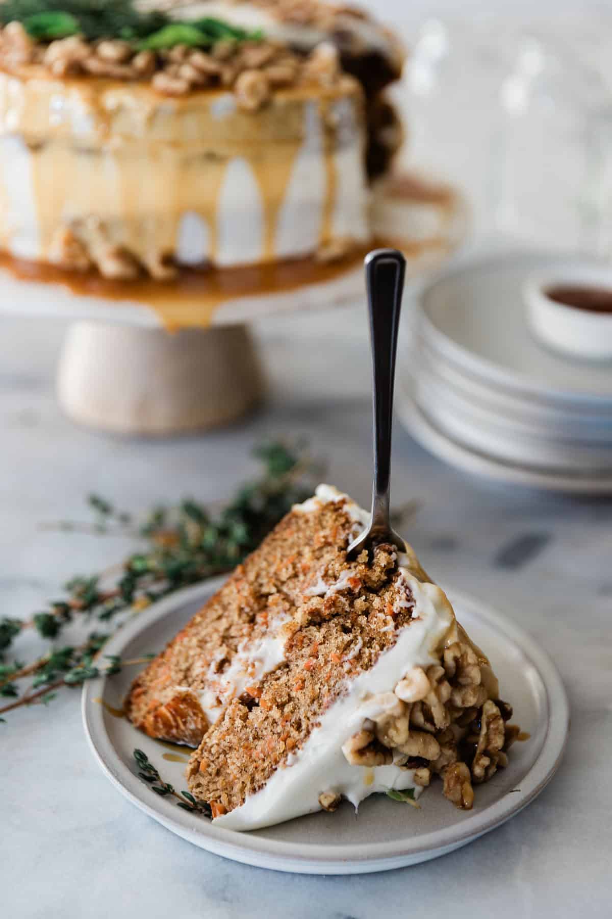 A slice of cake on a plate with a fork stuck in it.