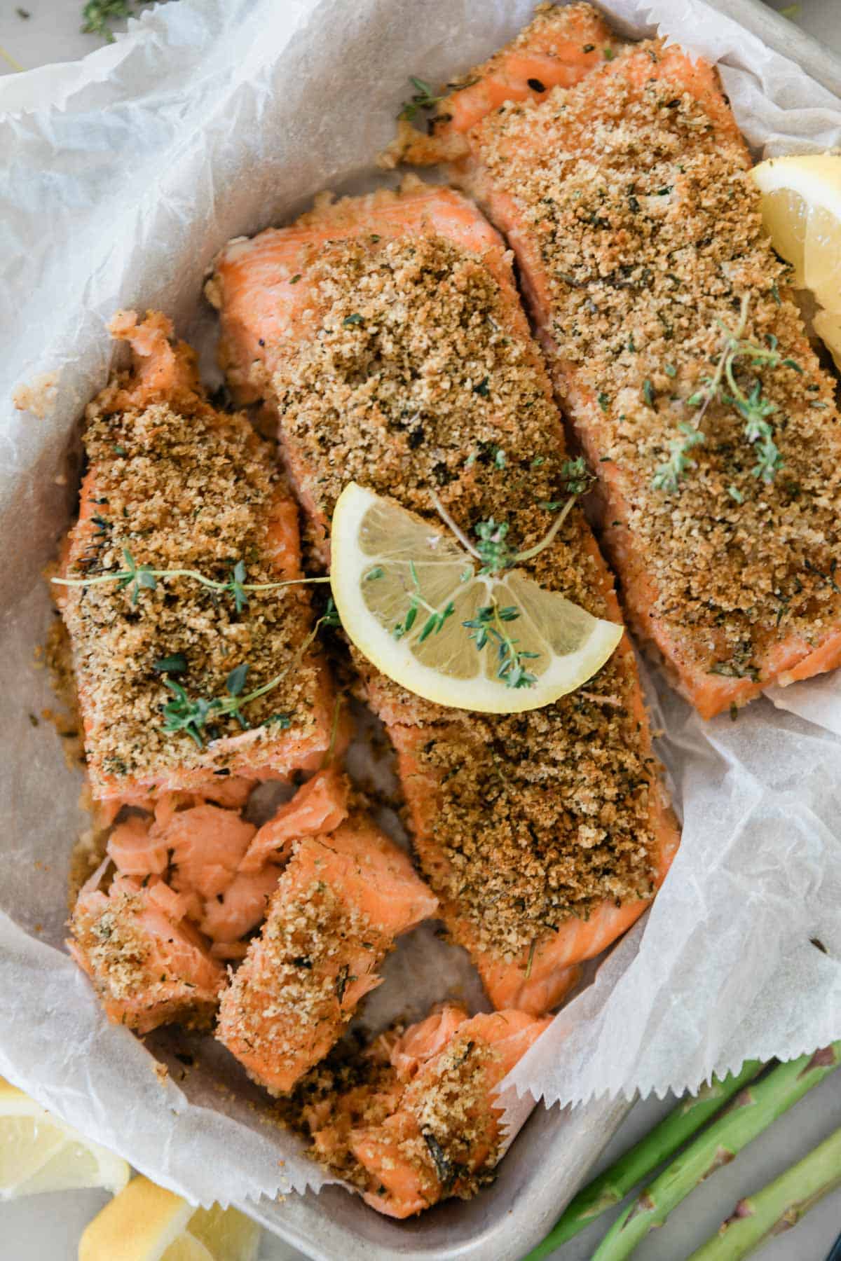 Herb crusted salmon on a platter garnished with a lemon slice.