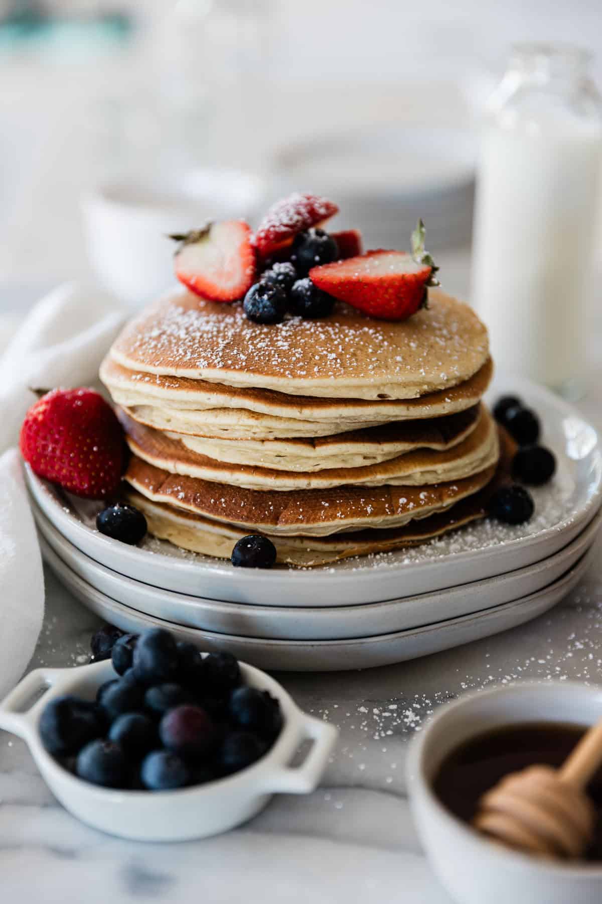 A stack of protein pancakes on a plate topped with fresh berries.
