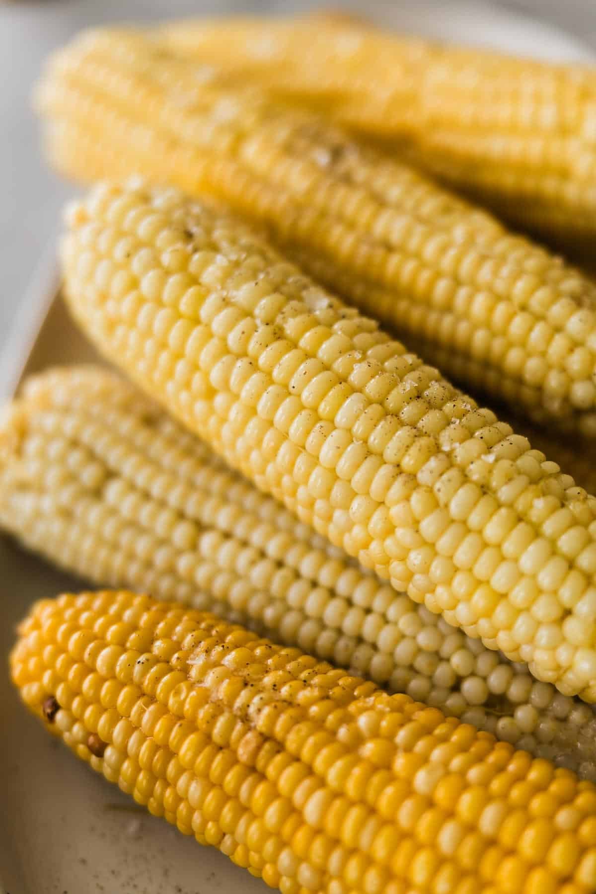 Cooked corn on the cob laid on top of each other at different angles.