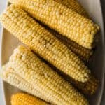 The best corn on the cob on a platter sprinkled with salt and pepper.