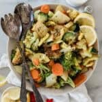 A bowl of grilled vegetable salad with utensils resting on the edge.