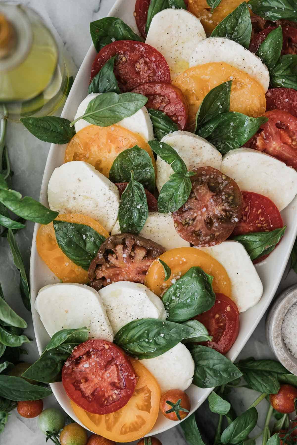 Caprese salad with colored tomatoes on an oval platter.