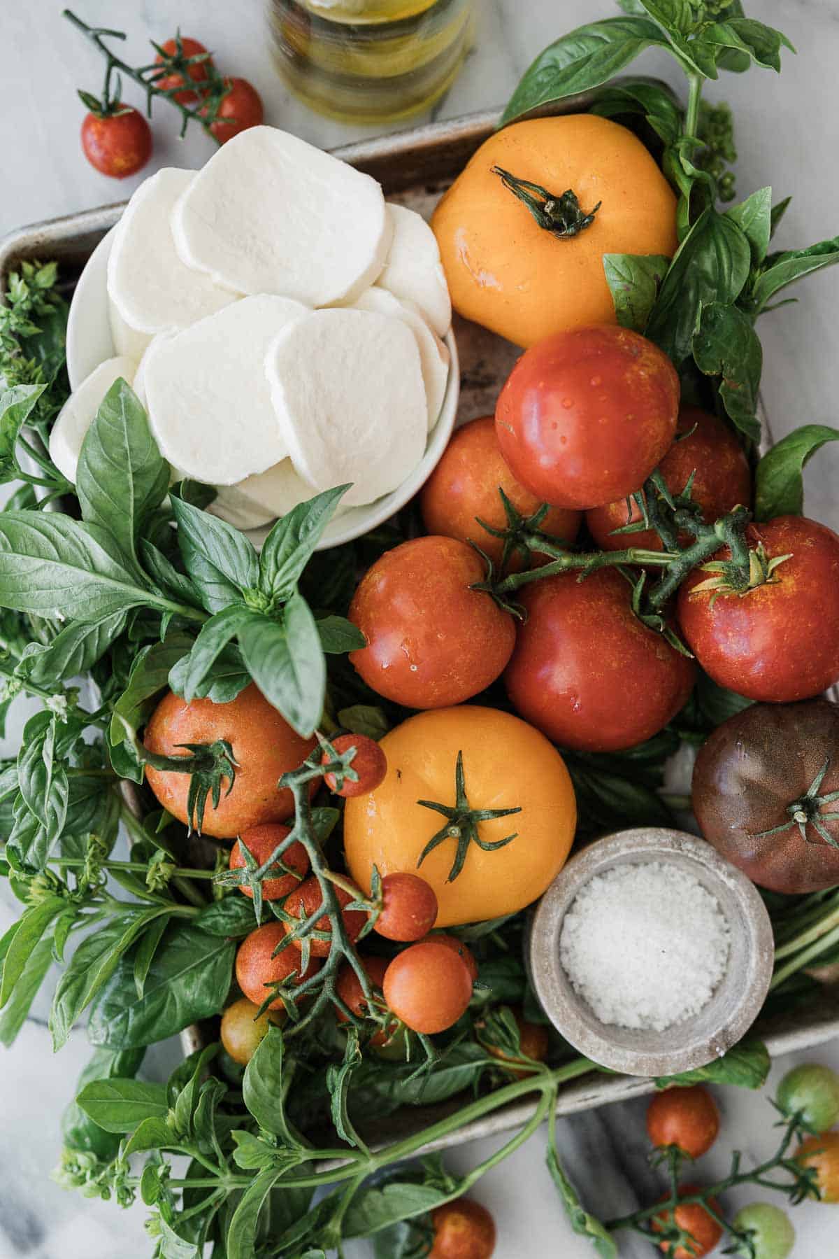 Ingredients to make an appetizer caprese salad laid out on a table.