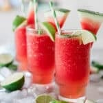 Watermelon slushies on a table scattered with ice and limes.