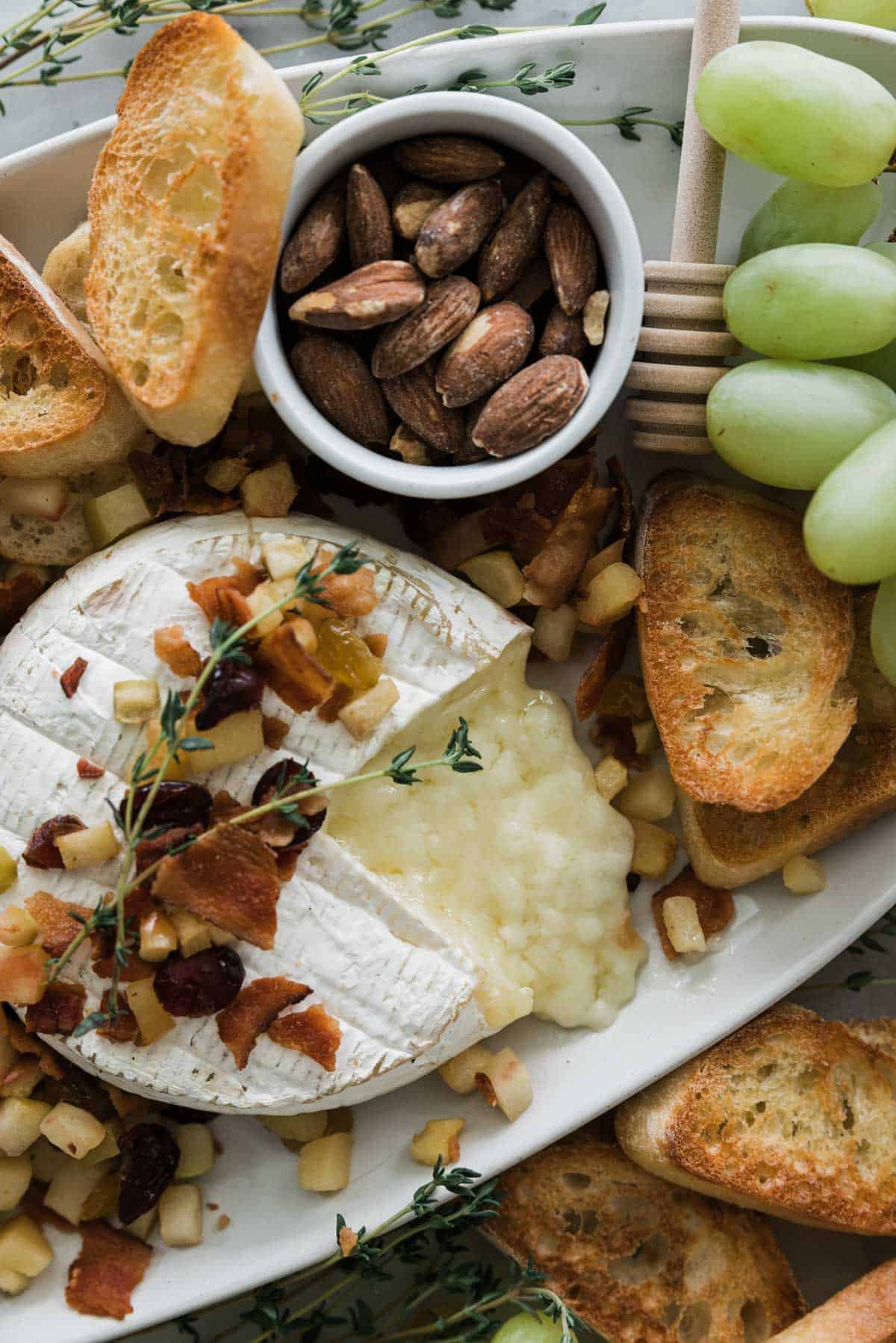 Baked brie with fruit topping on a platter.