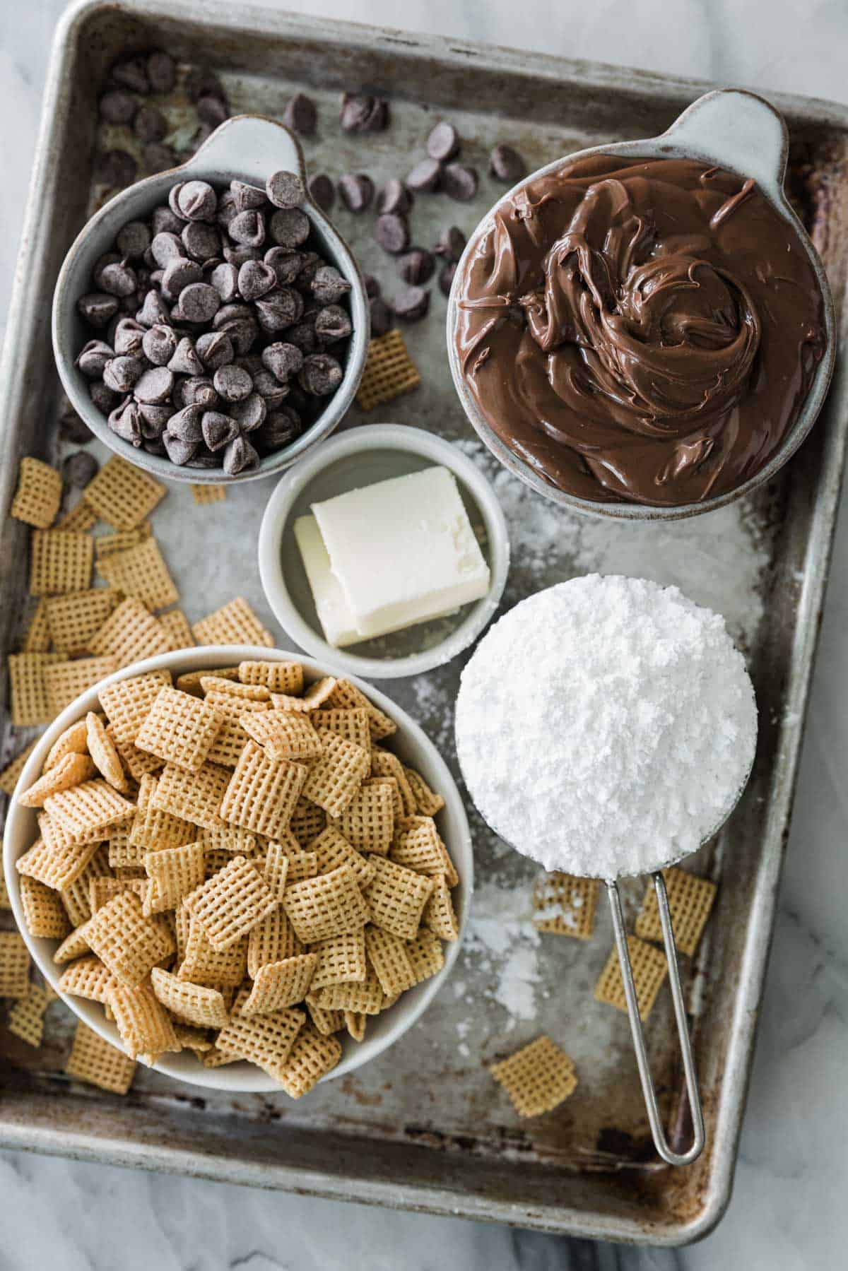 Ingredients for making Chex muddy buddies with Nutella. in bowls.