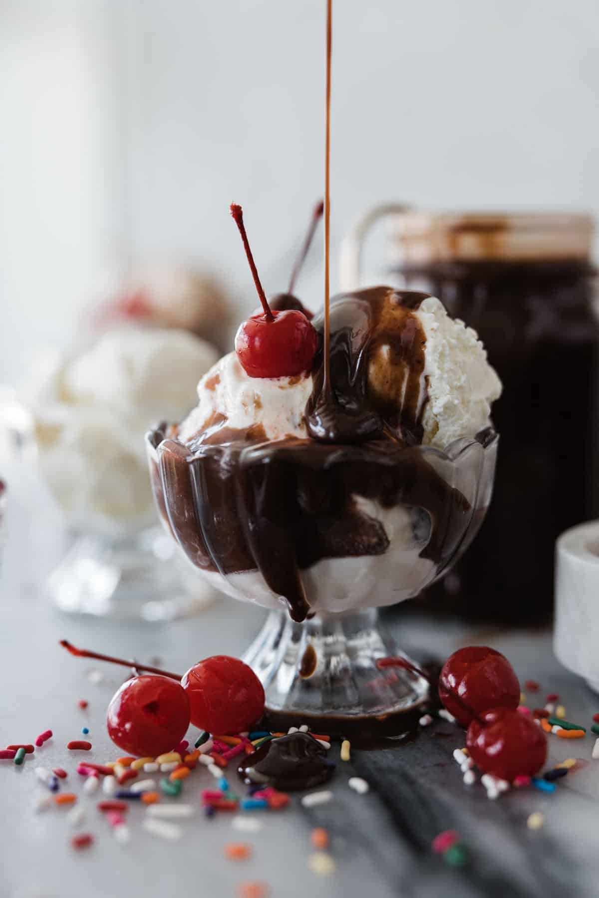 Hot fudge being poured on top of ice cream.