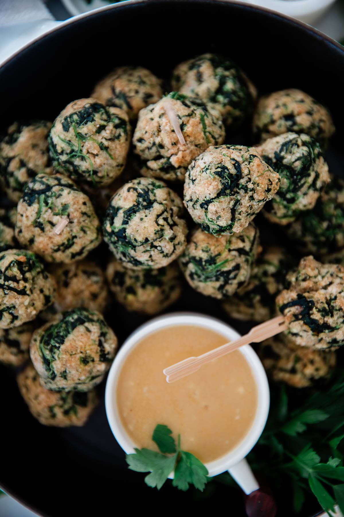 Spinach balls with dipping sauce in a skillet.