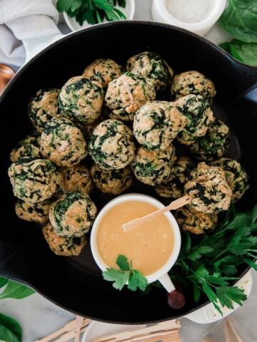Spinach balls with dipping sauce in a skillet.