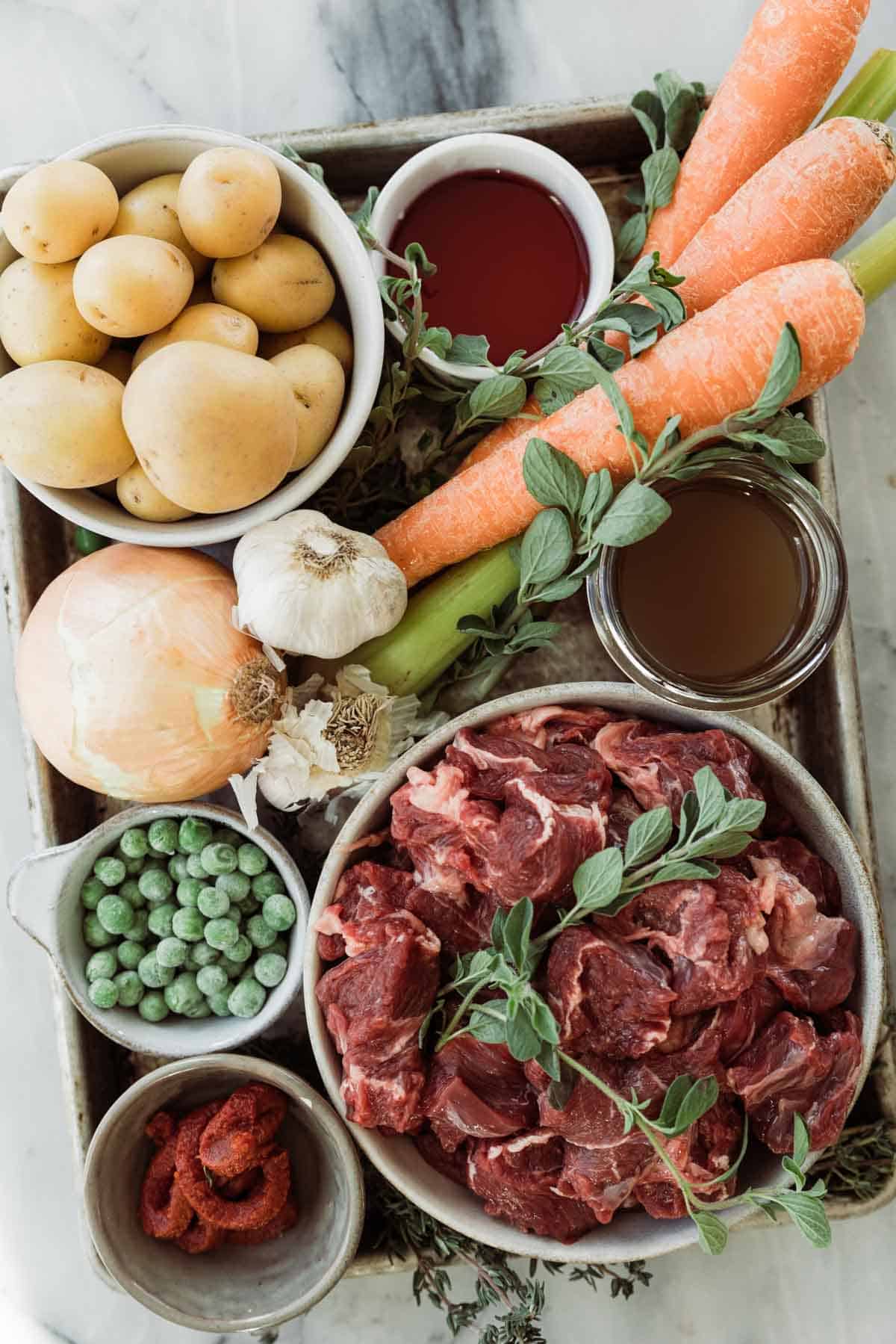 Ingredients to make homemade beef stew on a table in bowls. 