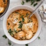 A bowl of sausage tortellini soup with a spoon in the bowl.