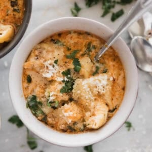 A bowl of sausage tortellini soup with a spoon in the bowl.