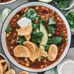 A bowl of easy taco soup with avocado, corn chips, sour cream on top.