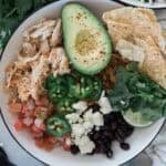 A chicken burrito bowl with veggies and chips.